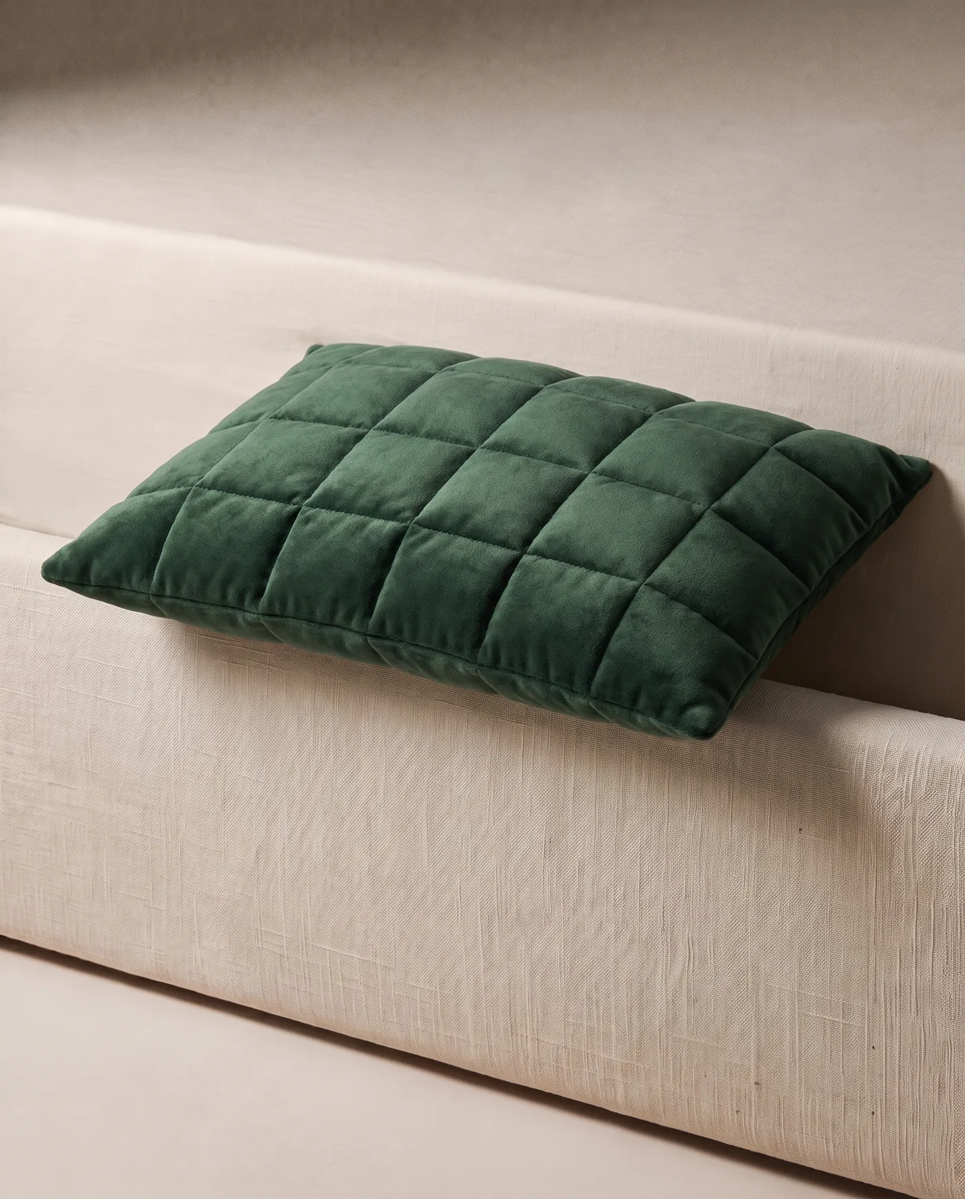 A forest green quilted velvet weighted lap pillow on a linen plinth.